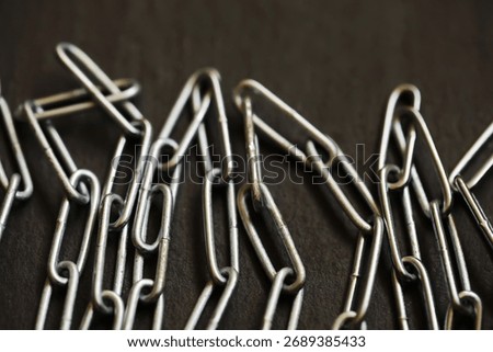 Close-Up of Interlinked Paper Clips on Dark Surface: Symbolizing Connection and Organization