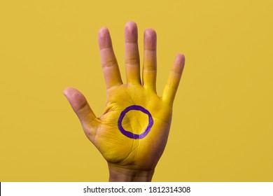 Closeup Of The Intersex Flag Painted In The Palm Of The Hand Of A Young Person, Against A Yellow Background With Some Blank Space Around It