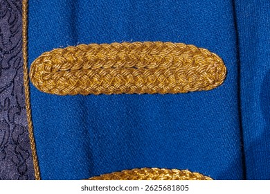 Close-up of intricately woven blue velvet fabric with golden-yellow embellishments, showcasing detailed embroidery patterns Soft diffused lighting enhances the texture and depth of the material Sty