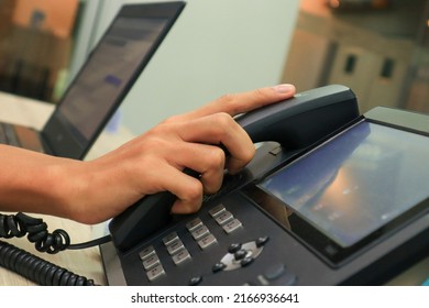 Close-up IP phone on the work desk, The human hand lifted the telephone placed on the table, Hang up the telephone cord placed on the work desk. - Shutterstock ID 2166936641