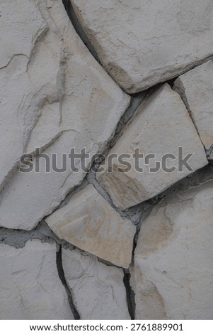 Close-up of irregular stone wall with rough texture and cracks