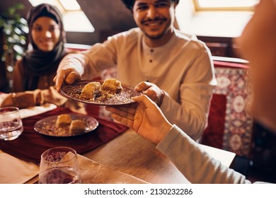 Close-up Of Islamic Family Eating Baklava At Dining Table At Home.