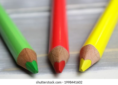 Closeup of isolated colorful yellow, red, green crayons on wood background - traffic light coalition concept (focus on tip of green pencil) - Shutterstock ID 1998441602