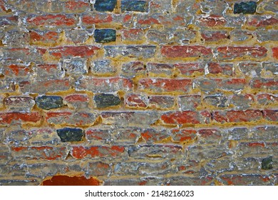 Closeup of isolated old medieval brick stone wall with faded pale washed out red grey colors