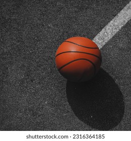 close-up isometric photograph of a basketball on court ground that is black and white. ball is orange