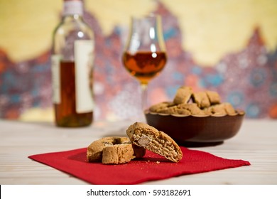 Closeup of Italian cantucci biscuits on a red napkin and vin santo wine on background