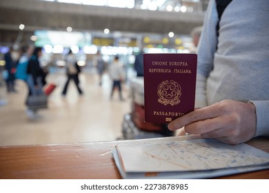 Close-up of an Italian passport held by a traveler with a map beside it. - Shutterstock ID 2273878985