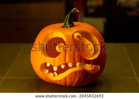 Closeup of a jack-o-lantern isolated on the kitchen counter. Funny halloween pumpkin face.