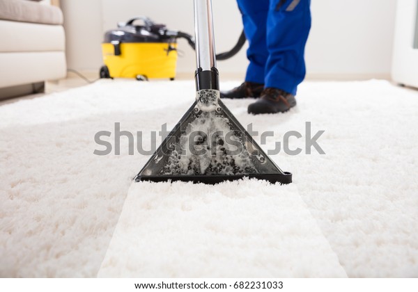 Close-up Of A Janitor Cleaning Carpet With Vacuum\
Cleaner At Home