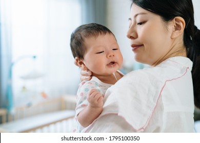 Closeup Japanese Mother With Cloth On Shoulder Is Burping Her Child. Asian Lovely Baby Held By Her Mummy Is Drooling. 