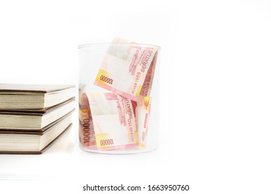 Closeup of jar filled with money papers near stack of books, isolated in white background