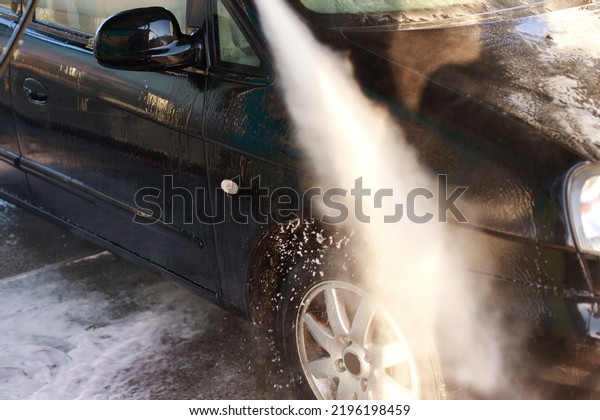 close-up of a jet of water from a sprayer washes a\
car at a self-service car\
wash