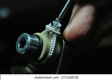 Close-up of a jeweler precisely setting a diamond into a ring, highlighting detailed craftsmanship and jewelry making skills. - Powered by Shutterstock