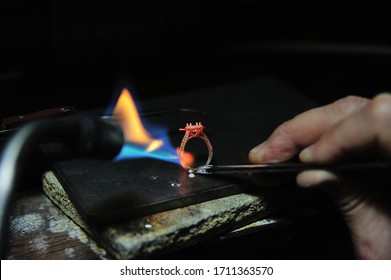 Close-up of a jeweler using a blowtorch to solder a ring, showcasing the precision and craftsmanship involved. - Powered by Shutterstock