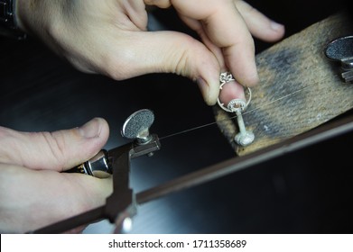 Close-up of a jeweler using a saw to cut a silver ring, highlighting the intricate process of jewelry making. - Powered by Shutterstock