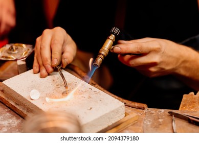 close-up of jeweler's hands working with a blowtorch on a piece of silver jewelry in his workshop. - Powered by Shutterstock