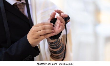   Un primer plano de un muchacho judío del bar mitzvah, vestido con una camisa blanca y un traje negro, se puso tefillin por primera vez en la pared occidental - jerusakem