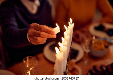 Close-up Of Jewish Man  Lightning The Menorah During Family Dinner At Dining Table On Hanukkah.