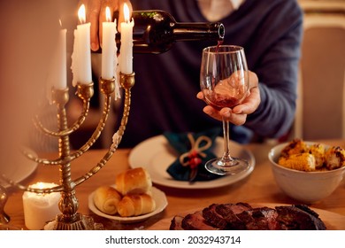 Close-up Of Jewish Man Pouring Wine Into A Glass While Having Traditional Dinner On Hanukkah.