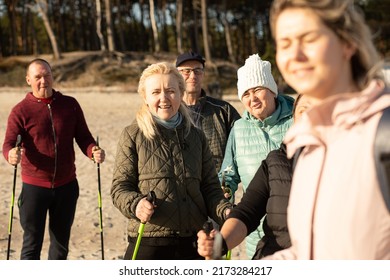 Close-up Of Joying Woman Blinking In The Sunlight And People Group, Nordic Walking With Trekking Sticks Outdoors. Weekend Activity For Campers. Workout Education, Breathing Technic And Leg Postures. 