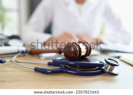 Closeup of judge gavel of stethoscope doctor in background writing notes. Concept of legal aspects of healthcare and medical insurance payments Imagine de stoc © 
