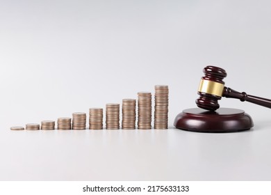 Close-up of judge wooden gavel and stack of golden coins. Money pyramids and bankruptcy or auction concept