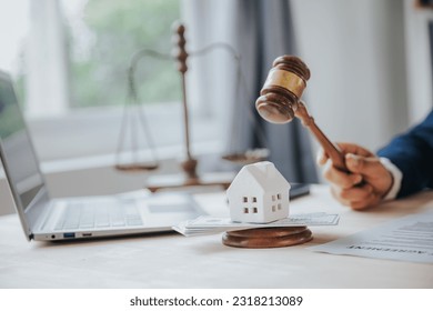 Close-up of a judge's hammer small wooden toy house On the table in the courtroom concept of real estate law division of property Land separation and divorce - Shutterstock ID 2318213089