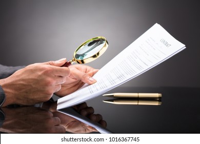 Close-up Of A Judge's Hand Looking At Document With Magnifying Glass - Shutterstock ID 1016367745