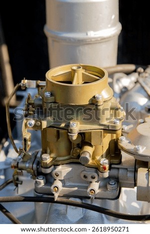 Close-up of a K126I carburetor, a complex mechanical component of an engine, featuring various levers, screws, and linkages.