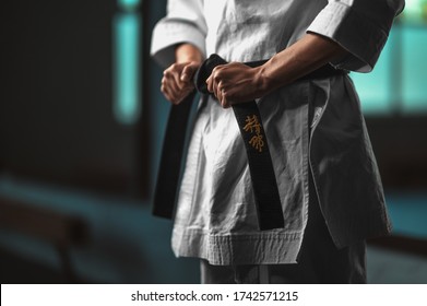 Close-up karate girl tightening  black belt - on belt Kaishin wich means "Open Mind"