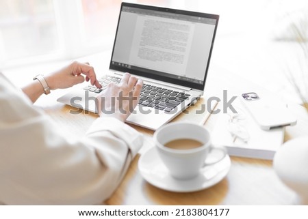 Close-up of keyboard keys on a laptop. Women's hands are typing text in a document. Buisness process.