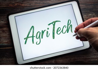 Closeup keyword Agritech (Agricultural technology) on tablet. Concept of technology in agriculture with the aim of improving yield, efficiency, and profitability. Man hand holding wireless stylus pen