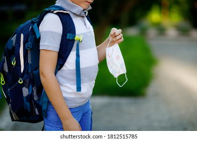 Close-up Of Kid Boy With Medical Mask And Backpack Or Satchel. Schoolkid On Way To School. Child Outdoors. Back To School After Quarantine Time From Corona Pandemic Disease Lockdown. No Face.