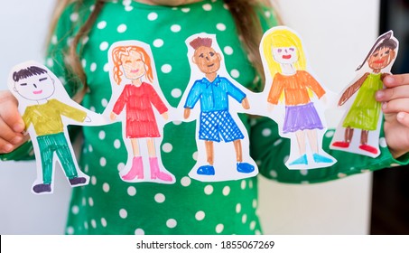 Close-up kid girl holding paper homemade garland with painted children of different races. Happy  international  children s day