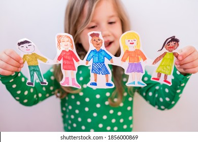 Close-up kid girl holding paper homemade garland with painted children of different races. Happy  international  children s day