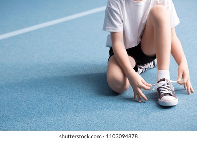 Close-up of kid tying a shoe on blue floor at the gym - Powered by Shutterstock