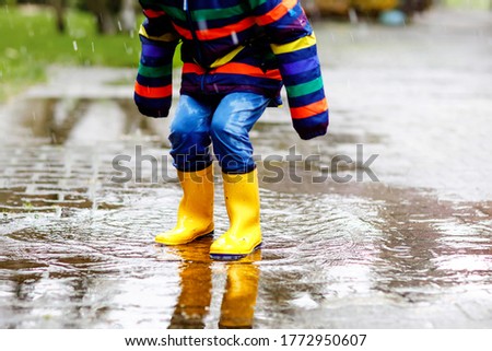 Similar – Image, Stock Photo Small infant boy wearing yellow rubber boots and yellow waterproof raincoat standing in puddle on a overcast rainy day. Child in the rain.