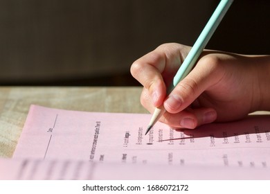 Closeup of kid's hand holding a pencil writing on a workbook. - Shutterstock ID 1686072172