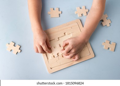 Closeup Of Kids Hands Playing With Puzzles On Blue Background With Blank Space For Text. Top View, Flat Lay Of Little Children Playing Puzzle At Table