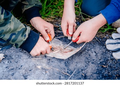 Close-up of kids hands using a fire striker at a survival camp