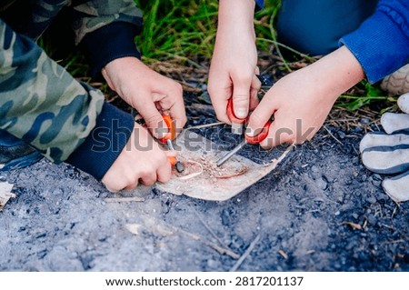 Close-up of kids hands using a fire striker at a survival camp
