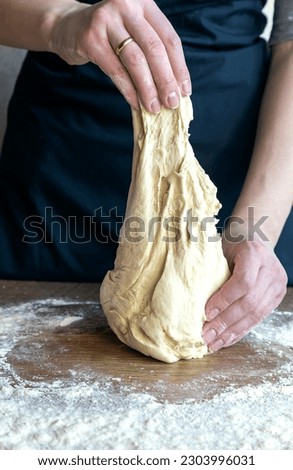 Close-up of kneaded dough in female hands. The process of kneading the dough.