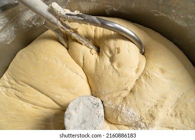Close-up of kneading elastic dough for bread in a kneading machine in a bakery. Industrial mixer for kneading dough.