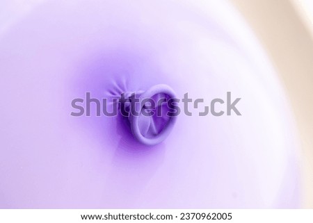 A closeup of the knot in the neck and lip of a purple balloon. The festive decoration is ready to be used to play with by children or adults and have some fun at a birthday party or anniversary.