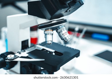 Close-up of a laboratory microscope focusing on objective lenses and specimen stage, representing tools used in scientific research, medical diagnostics, and microbiological or biochemical analysis.