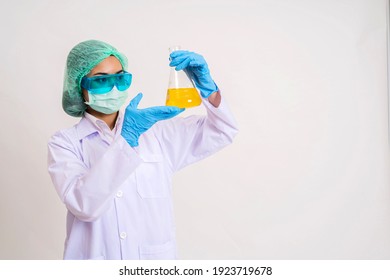 Close-up Of Laboratory Researcher Holding Medical Glass Bottle With Yellow Liquid Wearing Sterile Gloves And Special Lab Eyewear. Scientist Woman At Job. Chemistry Concept