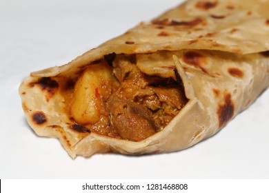Close-up of a lamb roti roll - an Indian bread with lamb curry as a filling, a popular Indian dish / takeaway food in South Africa (shallow depth of field effect) - Shutterstock ID 1281468808