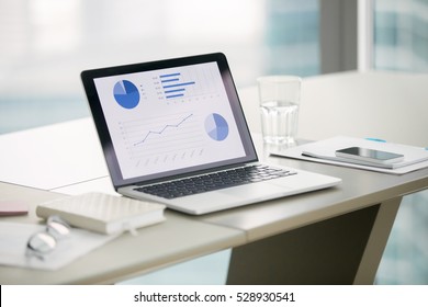 Closeup of laptop with graphs on screen on white modern office desk, preparation for formal meeting of the board of directors, effective management. Office interior. Business success concept. Close up - Powered by Shutterstock