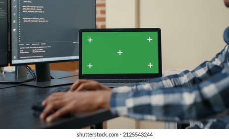 Closeup Of Laptop With Green Screen Chroma Key Mockup And African American Hands Writing Code On Computer Keyboard. Programer Developing Software In Front Of Multiple Screens Running Ai Algorithm.