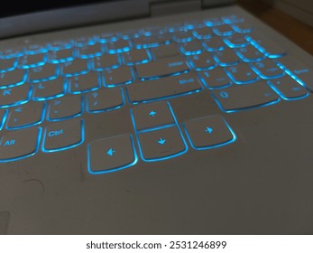 A close-up of a laptop keyboard illuminated with soft blue LED backlight, enhancing visibility and usability in dark environments. Perfect for late-night work or gaming sessions in low light - Powered by Shutterstock